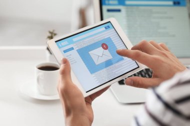 Tabletli genç adam evde e-postalarını kontrol ediyor.
