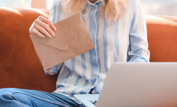 Young woman with letter and laptop at home