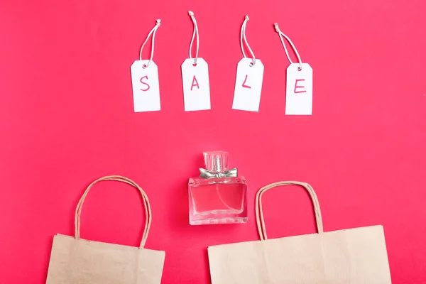 色の背景にショッピングバッグと販売のための香水のボトル — ストック写真