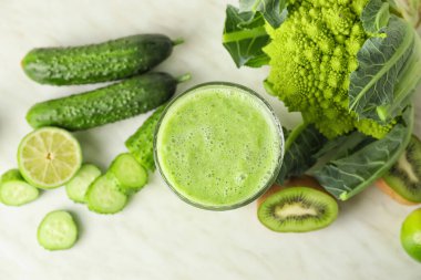 Masada bir bardak sağlıklı meyve püresi ve malzeme var.