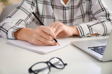 Yetişkin bir kadın evde online öğrenim için dizüstü bilgisayar kullanıyor.