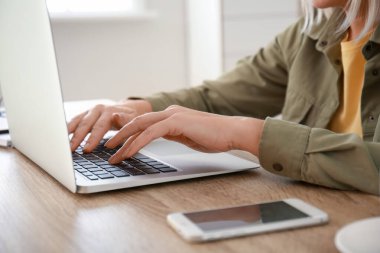 Yetişkin bir kadın evde online öğrenim için dizüstü bilgisayar kullanıyor.