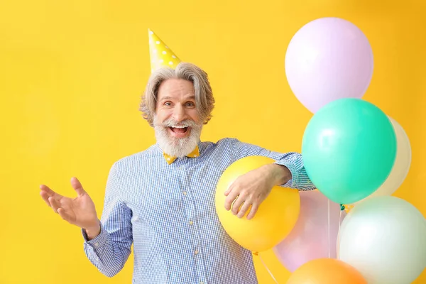 Senior man celebrating Birthday on color background