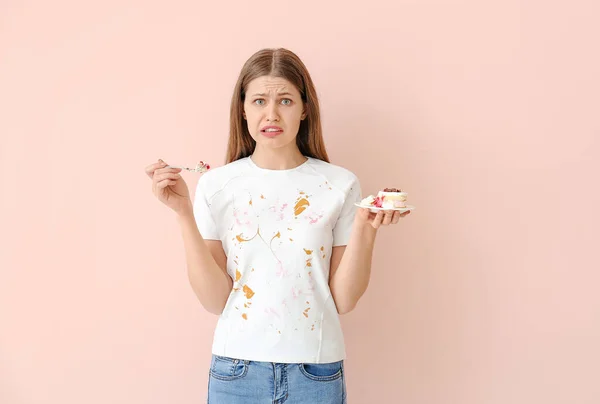 衣衫褴褛的女人吃着彩色背景的甜点 — 图库照片