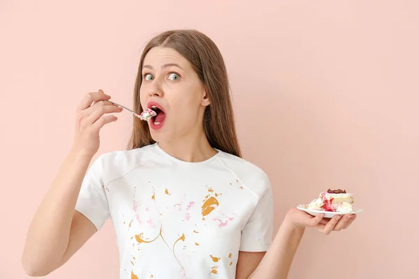 汚れた服の女性は色の背景にデザートを食べる — ストック写真