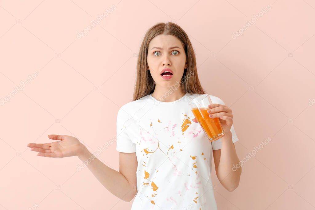 Troubled woman in dirty clothes drinking juice on color background