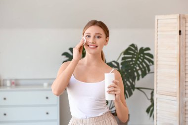 Güzel genç bayan evde makyajı temizliyor.