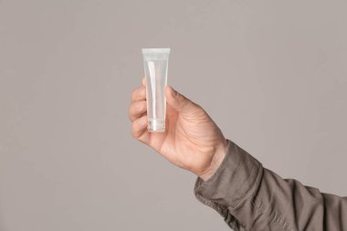 Gri arka planda dezenfektanı olan adam.