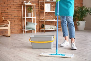 Genç bir kadın odayı paspaslıyor.