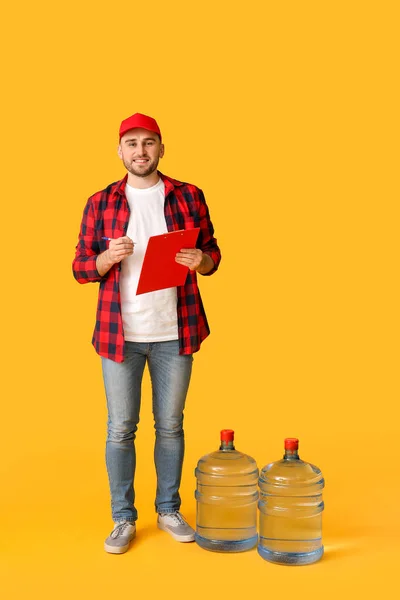 Delivery man with bottles of water on color background
