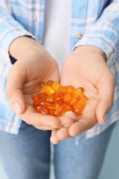 Woman with fish oil capsules, closeup