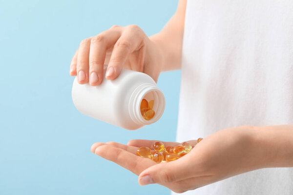 Woman with fish oil capsules, closeup