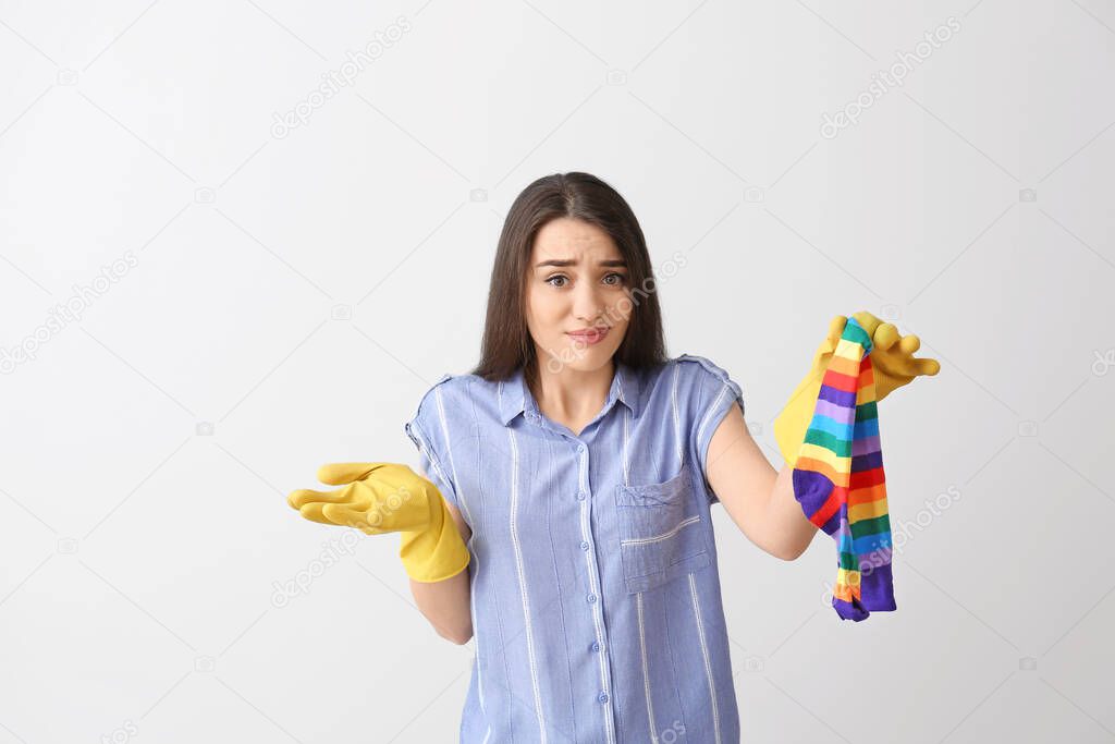 Displeased young woman with dirty socks on light background