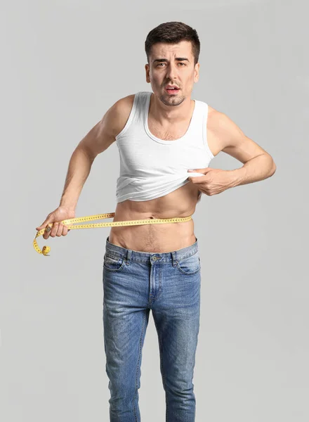 病人在灰色背景下测量他的腰围 厌食症的概念 — 图库照片