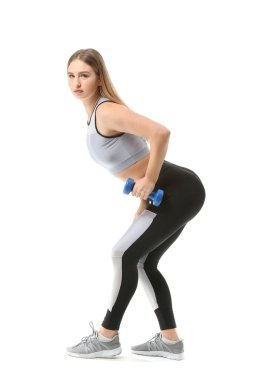 Beyaz arka planda dambıllarla spor yapan genç bir bayan.