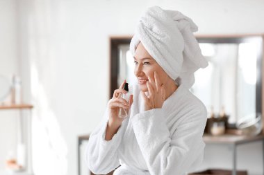 Tuvalette makyaj malzemesi kullanan olgun bir kadın.