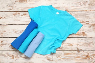 Beyaz ahşap arka planda farklı tarz tişörtler.