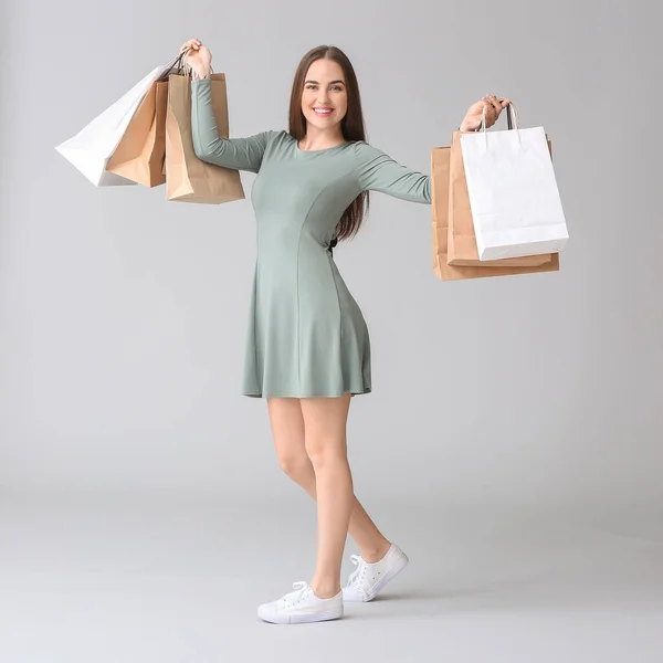 Junge Frau Mit Einkaufstaschen Auf Grauem Hintergrund — Stockfoto