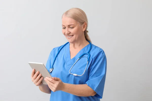 Médica Madura Com Computador Tablet Fundo Claro — Fotografia de Stock