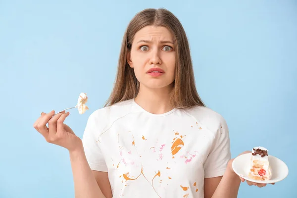 色の背景でデザートを食べる汚れた服のトラブル女性 — ストック写真