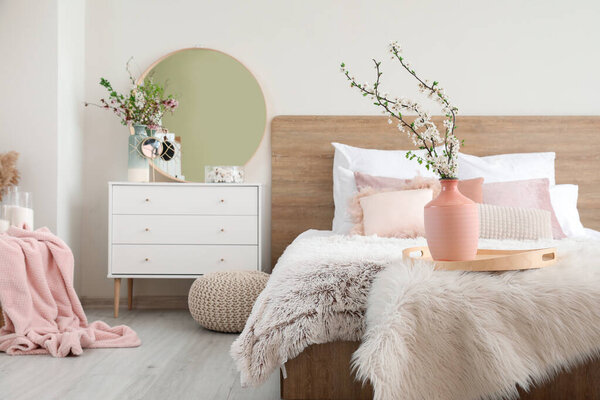 Interior of beautiful modern bedroom with spring flowers