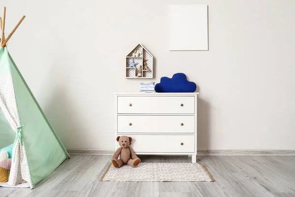 Chest of drawers with clothes and toys in children\'s room