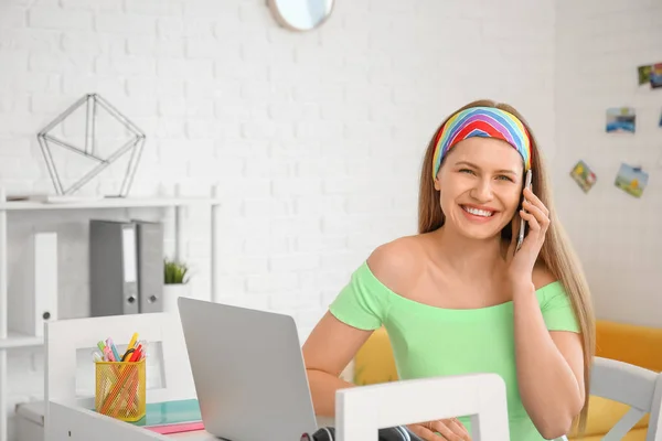 Young woman with laptop and mobile phone working at home