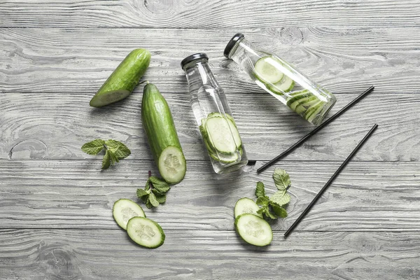 Bottles of infused cucumber water on wooden background
