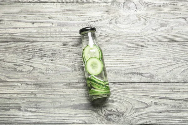 Bottle of infused cucumber water on wooden background