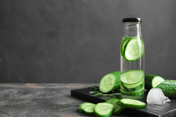 Bottle of infused cucumber water on dark background