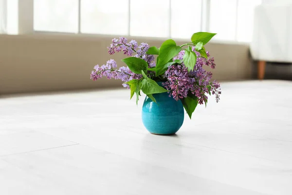 Vase with beautiful lilac flowers on floor in room