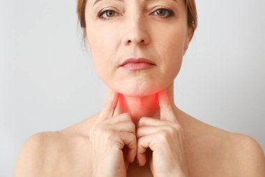 Gri arka planda tiroit bezi sorunu olan olgun bir kadın.