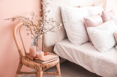 Bahar ağacı dalları, mumlar ve kitaplarla dolu bir vazo.