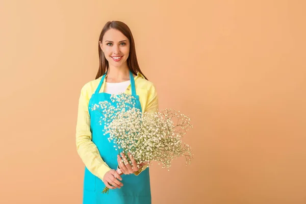 Portrait of female florist with bouquet on color background