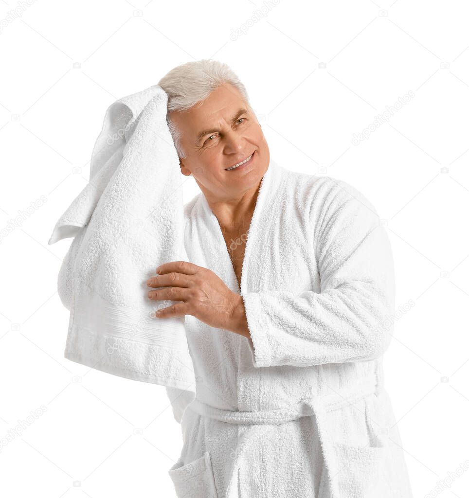 Happy mature man in bathrobe and with towel on white background