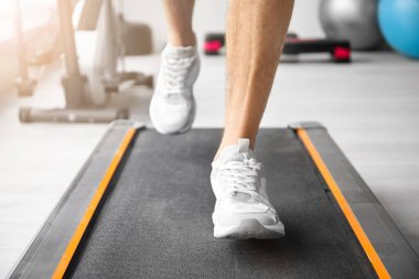 Genç adam spor salonunda koşu bandında antrenman yapıyor.