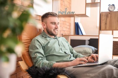 Bilgisayarlı genç adam evde çalışıyor.