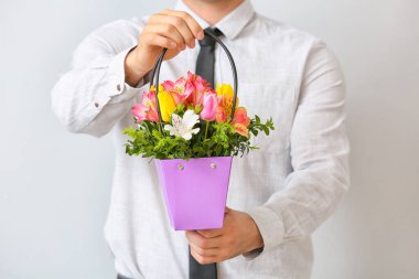 Açık arkaplanda çiçek demeti olan yakışıklı bir adam.