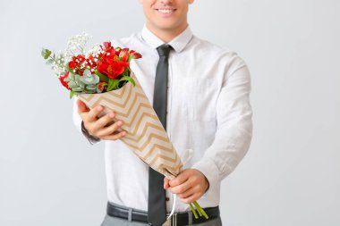 Açık arkaplanda çiçek demeti olan yakışıklı bir adam.