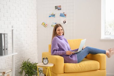 Evde çalışan dizüstü bilgisayarı olan genç bir kadın.