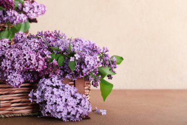 Masanın üzerinde güzel leylak çiçekleri olan sepet.