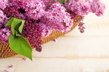 Açık arkaplanda güzel leylak çiçekleri olan sepet.