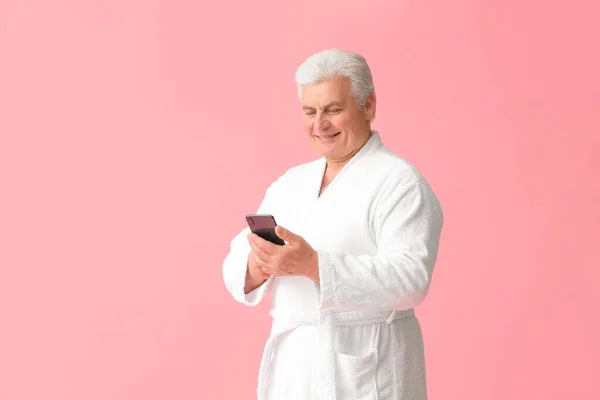 穿着浴衣 带着彩色背景手机的成熟快乐男人 — 图库照片