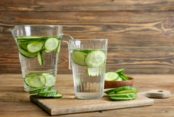 Glass and jug of cucumber infused water on table