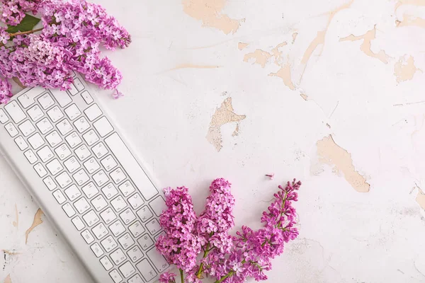 Beautiful lilac flowers and PC keyboard on table