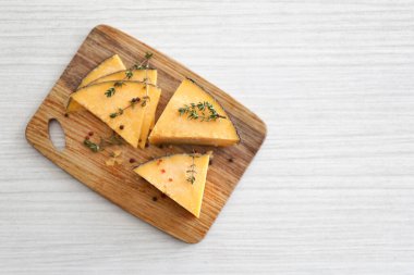 Lezzetli peynirli ahşap tahta, kekik ve baharatlar beyaz masada.