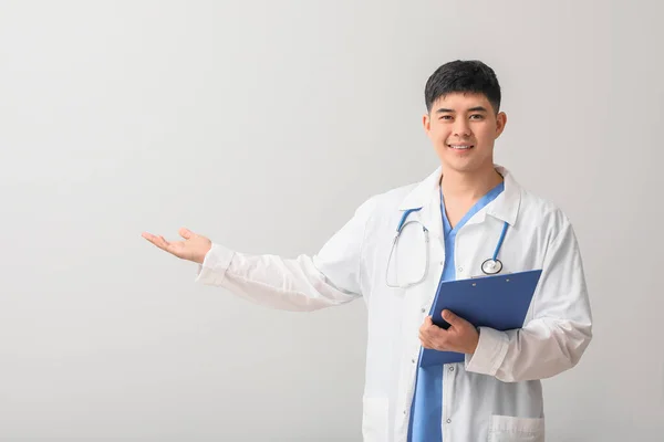 Masculino Asiático Doctor Con Portapapeles Mostrando Algo Luz Fondo —  Fotos de Stock