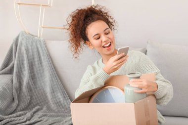 Yeni evinde fotoğraf çeken taşınma kutusuyla genç bir kadın.