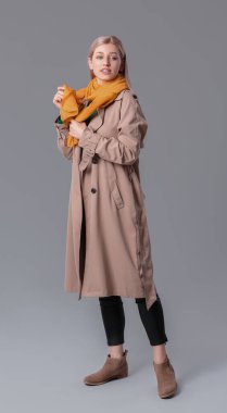 Gri arka planda şık bir eşarbı olan güzel bir genç kadın.