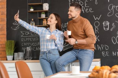 Meslektaşlar ofisin mutfağında kahve içerken selfie çekiyorlar.